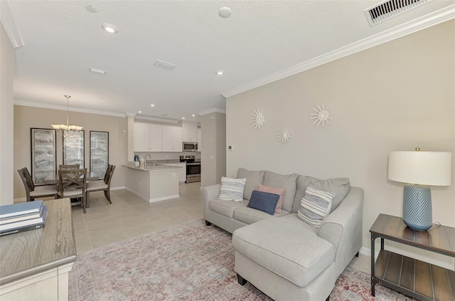 tiled living room featuring a textured ceiling, sink, ornamental molding, and a notable chandelier