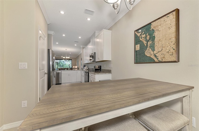 dining area featuring sink, ornamental molding, and a notable chandelier