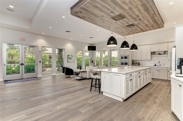 kitchen with light hardwood / wood-style floors, a kitchen island, white cabinetry, and pendant lighting