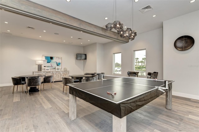 recreation room with beamed ceiling and light hardwood / wood-style flooring