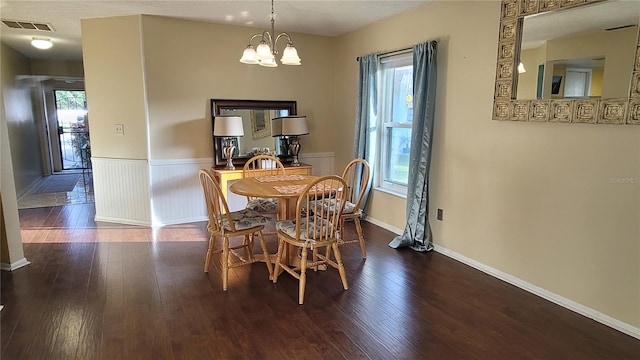 dining area featuring dark hardwood / wood-style flooring and an inviting chandelier