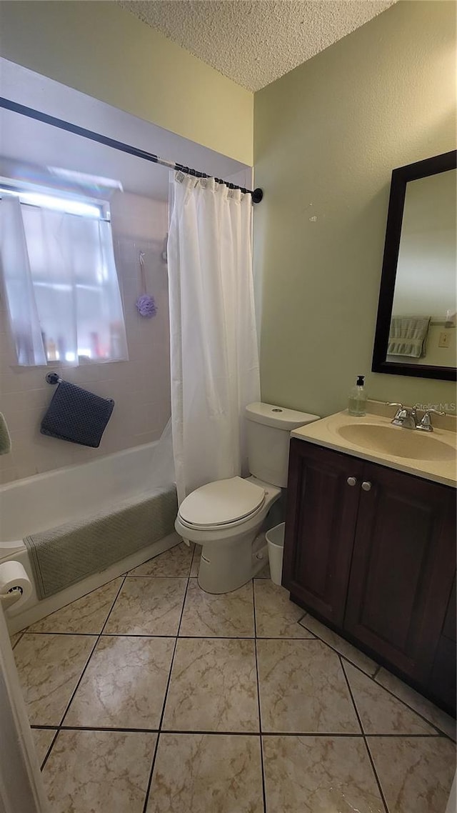 full bathroom with tile patterned floors, vanity, a textured ceiling, shower / bath combo with shower curtain, and toilet