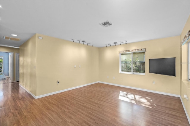 empty room with rail lighting and hardwood / wood-style flooring