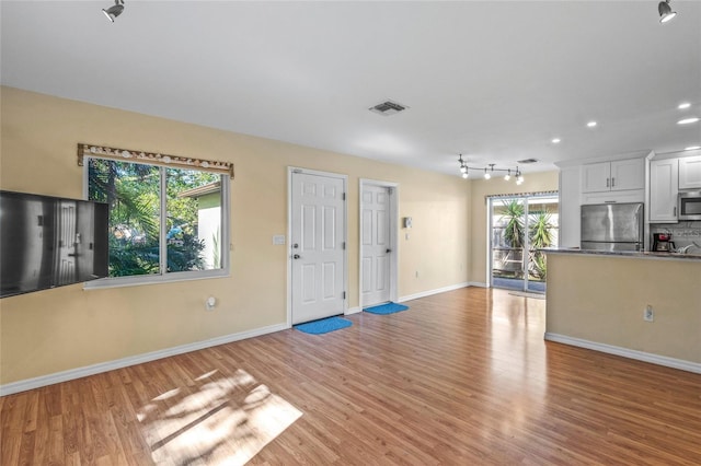 unfurnished living room with a healthy amount of sunlight and light wood-type flooring