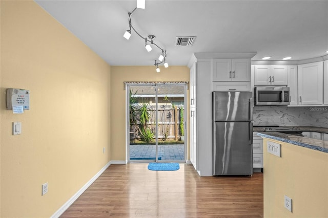 kitchen featuring decorative backsplash, white cabinetry, hardwood / wood-style floors, and stainless steel appliances