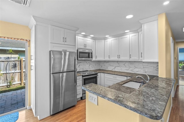 kitchen featuring kitchen peninsula, stainless steel appliances, white cabinetry, and a healthy amount of sunlight