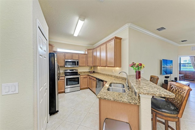 kitchen featuring a breakfast bar, sink, ornamental molding, appliances with stainless steel finishes, and kitchen peninsula