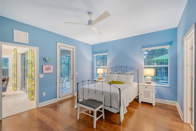 bedroom with access to outside, multiple windows, and light hardwood / wood-style floors