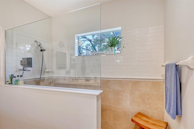 bathroom with a tile shower and tile walls