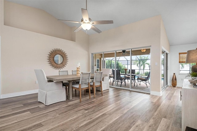 dining space with hardwood / wood-style flooring, ceiling fan, and lofted ceiling