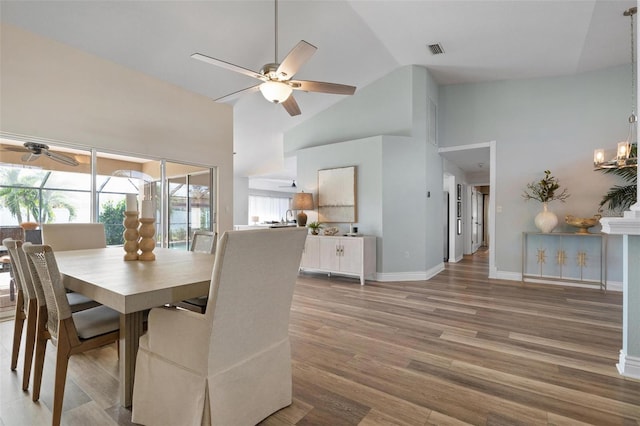 dining space with hardwood / wood-style floors, high vaulted ceiling, and ceiling fan