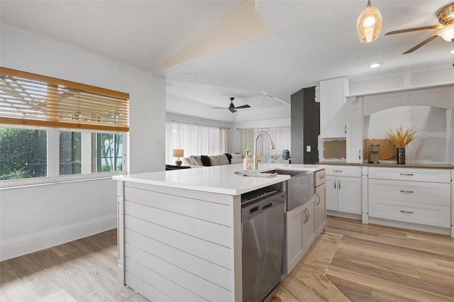 kitchen featuring stainless steel dishwasher, a kitchen island with sink, decorative light fixtures, light hardwood / wood-style floors, and white cabinetry