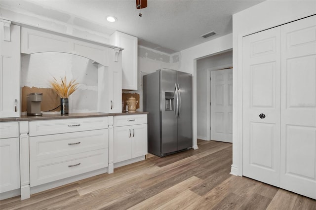 kitchen featuring white cabinets, stainless steel fridge, a textured ceiling, and light hardwood / wood-style floors