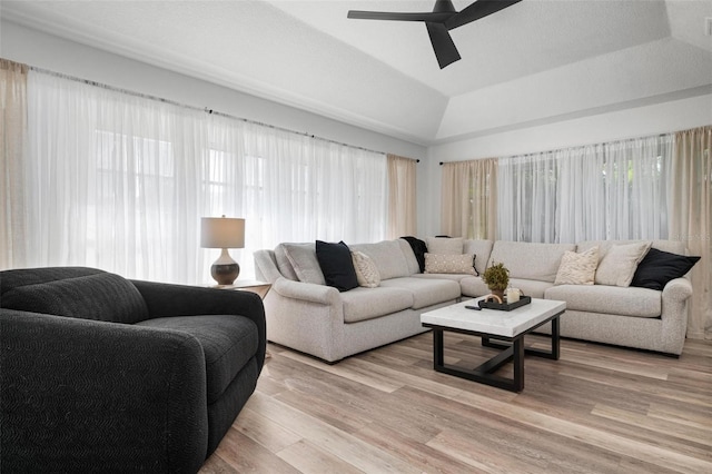 living room featuring light hardwood / wood-style floors, vaulted ceiling, and ceiling fan