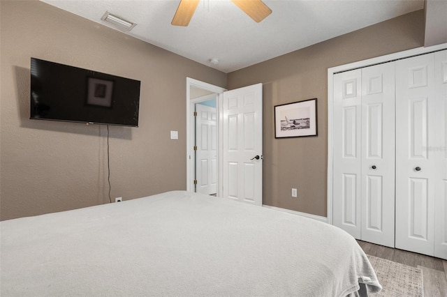 bedroom with ceiling fan, a closet, and wood-type flooring