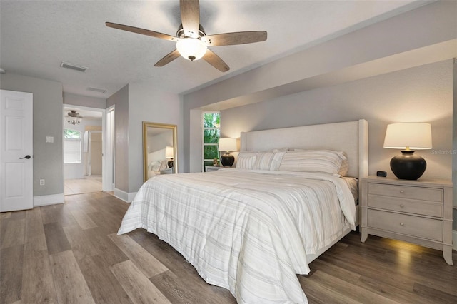 bedroom with a textured ceiling, hardwood / wood-style flooring, multiple windows, and ceiling fan