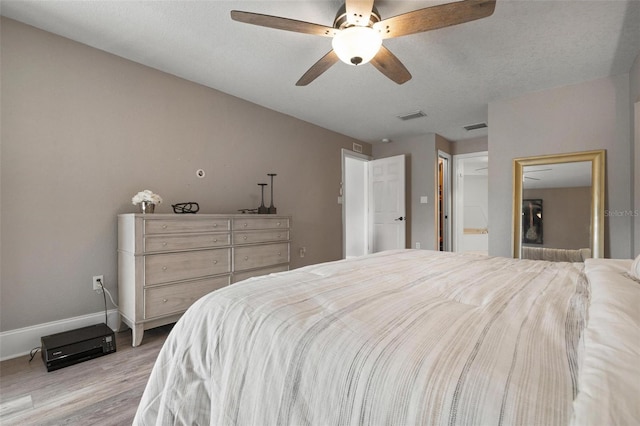 bedroom with ceiling fan, light hardwood / wood-style floors, and a textured ceiling