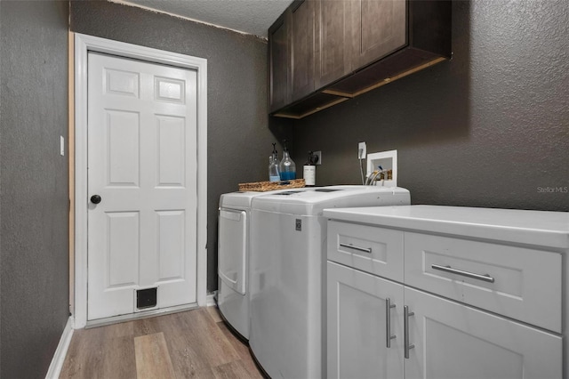 laundry room with cabinets, separate washer and dryer, and light wood-type flooring