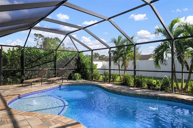 view of pool with a patio area, pool water feature, and glass enclosure