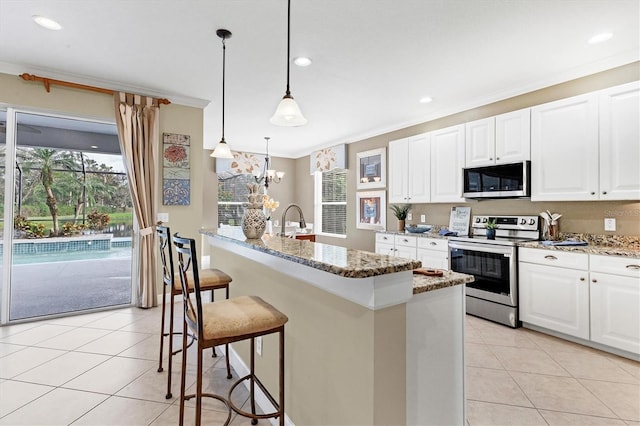 kitchen featuring pendant lighting, stainless steel appliances, light stone counters, and white cabinetry