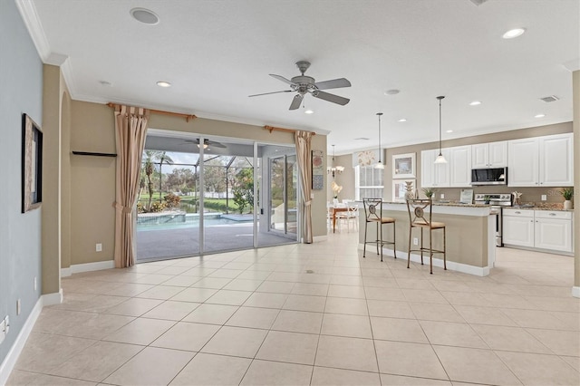 kitchen featuring white cabinets, a center island with sink, decorative light fixtures, light stone counters, and stainless steel appliances