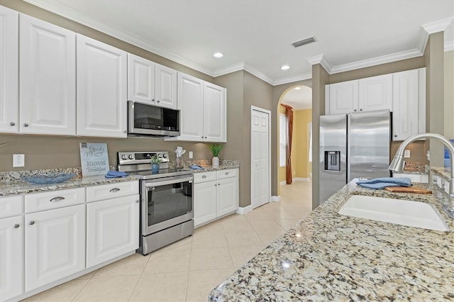 kitchen featuring white cabinets, crown molding, sink, light tile patterned floors, and stainless steel appliances