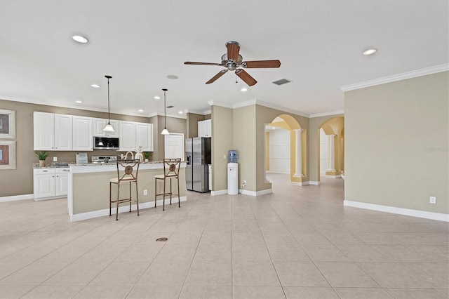 kitchen featuring pendant lighting, crown molding, an island with sink, appliances with stainless steel finishes, and white cabinetry