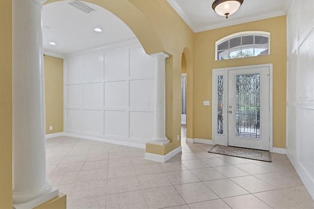 tiled entrance foyer with a healthy amount of sunlight, crown molding, and decorative columns