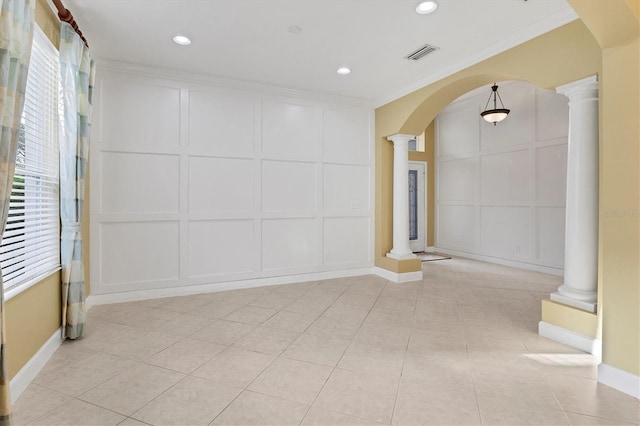 empty room with ornamental molding, light tile patterned floors, and decorative columns