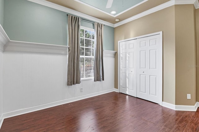 unfurnished bedroom featuring ceiling fan, ornamental molding, dark wood-type flooring, and a closet