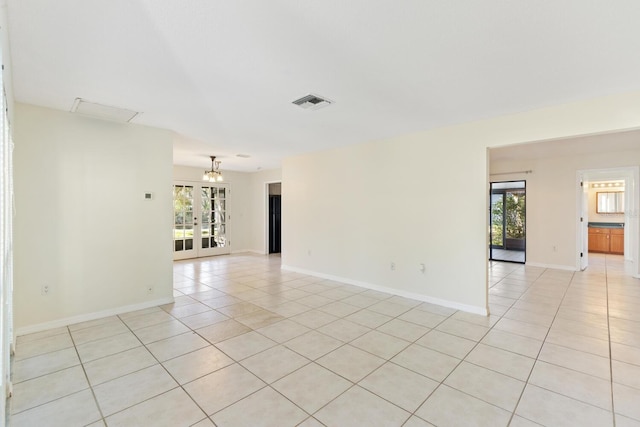 spare room with light tile patterned flooring and a chandelier