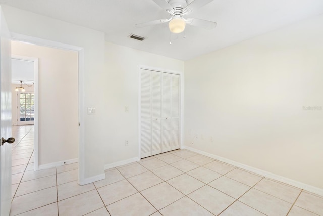 unfurnished bedroom featuring ceiling fan, light tile patterned floors, and a closet