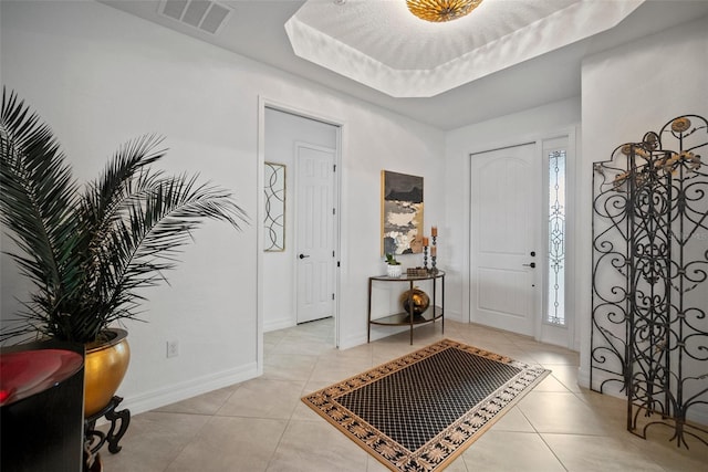 foyer entrance with a raised ceiling and light tile patterned floors