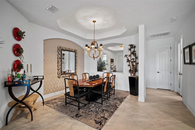 dining room with a raised ceiling, a textured ceiling, and a chandelier