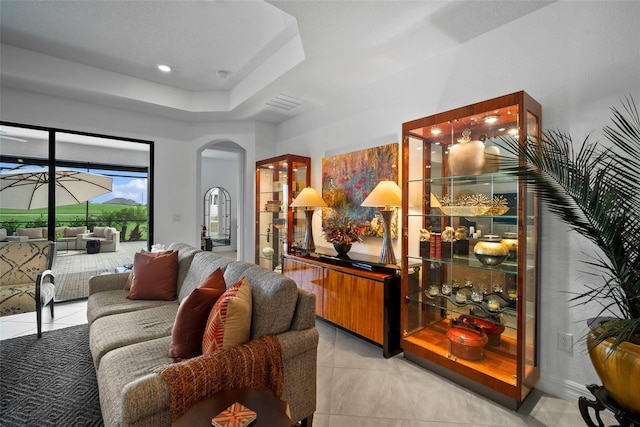 living room featuring a tray ceiling and light tile patterned floors