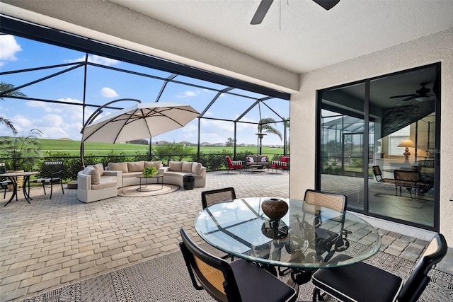 view of patio / terrace featuring an outdoor hangout area, glass enclosure, and ceiling fan