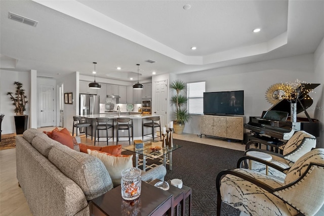 living room featuring a raised ceiling and sink