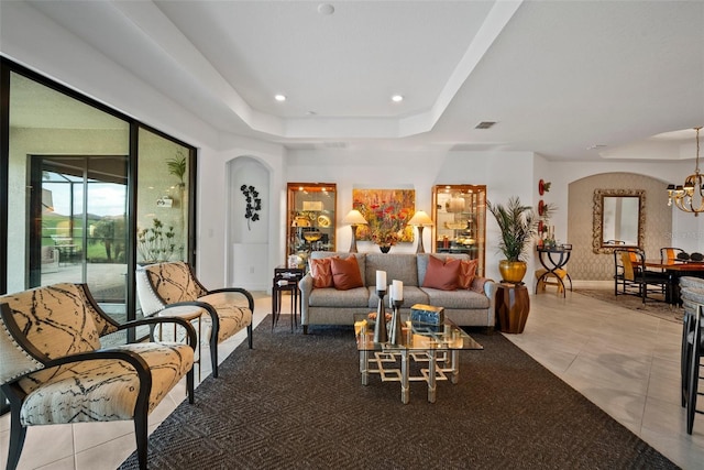 living room with a chandelier, light tile patterned floors, and a raised ceiling