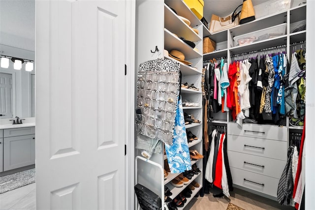 walk in closet with light tile patterned floors and sink