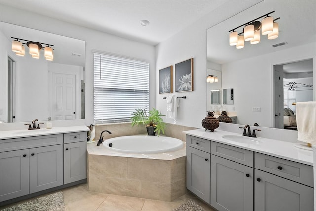 bathroom with tile patterned flooring, vanity, and tiled tub