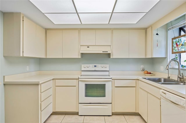 kitchen with cream cabinetry, light tile patterned floors, white appliances, and sink