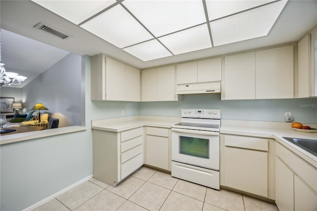 kitchen with white range with electric cooktop, light tile patterned floors, cream cabinetry, and an inviting chandelier