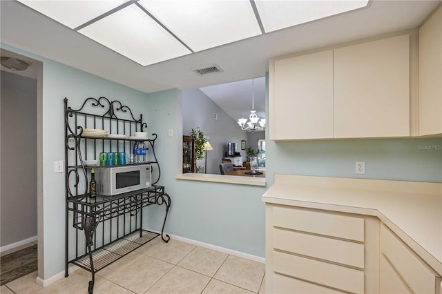 kitchen featuring light tile patterned floors, a chandelier, decorative light fixtures, and cream cabinetry