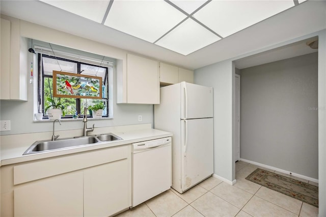 kitchen featuring sink, light tile patterned flooring, white appliances, and cream cabinetry