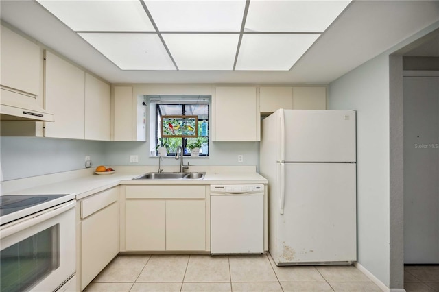 kitchen with cream cabinetry, light tile patterned flooring, white appliances, and sink