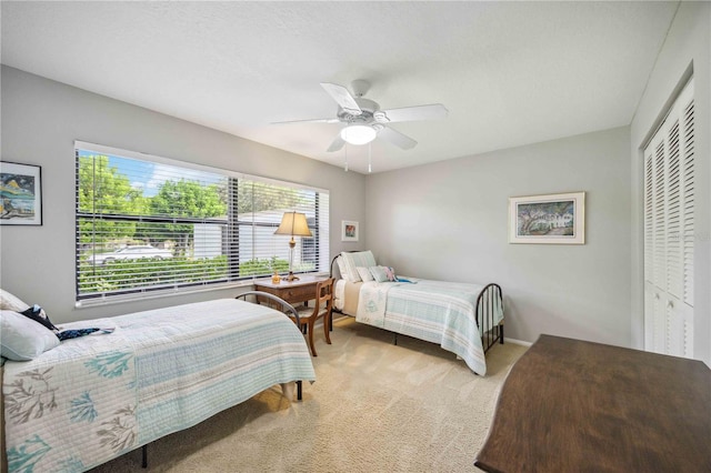 carpeted bedroom featuring ceiling fan and a closet