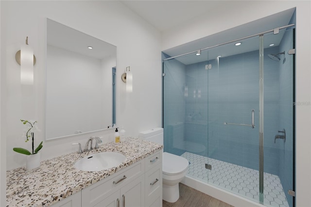 bathroom featuring walk in shower, hardwood / wood-style floors, vanity, and toilet