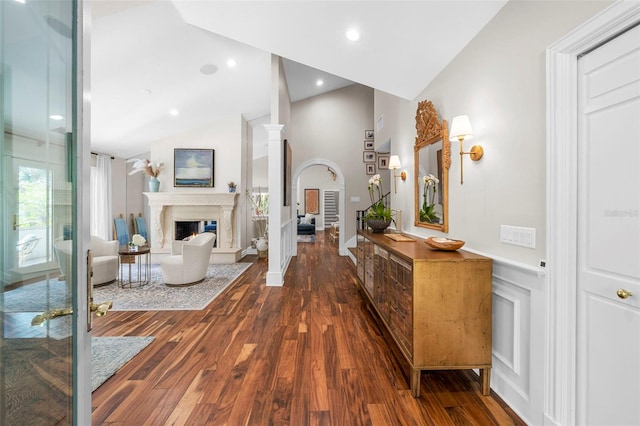 hall with dark hardwood / wood-style floors, vaulted ceiling, and ornate columns