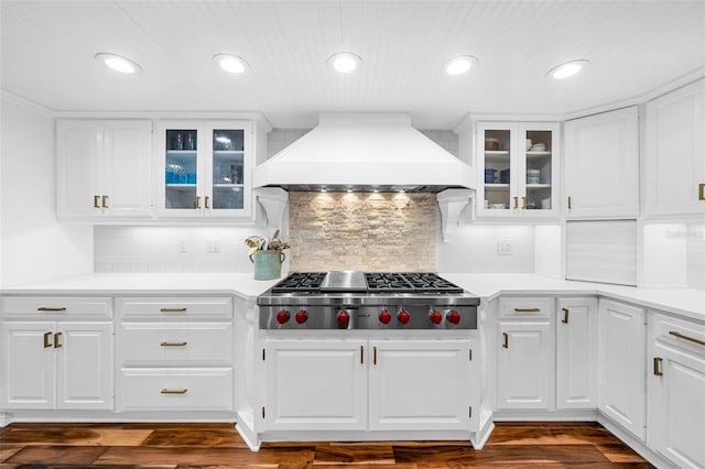 kitchen with backsplash, custom exhaust hood, stainless steel gas cooktop, dark wood-type flooring, and white cabinetry