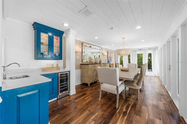 dining area with crown molding, sink, dark hardwood / wood-style flooring, beverage cooler, and a chandelier